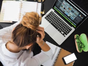 Stressed woman with computer and books around her