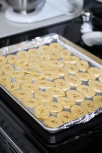 Sliced raw plantain on baking sheet