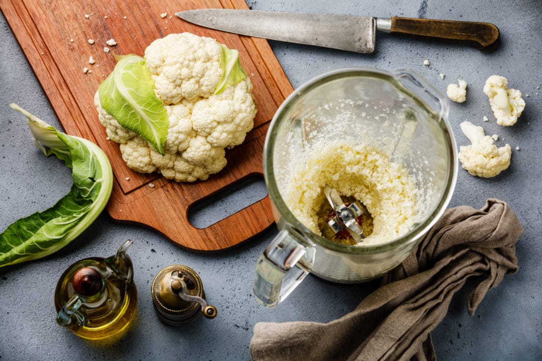 Raw Cauliflower ground in food processor for making Cauliflower Rice on concrete background