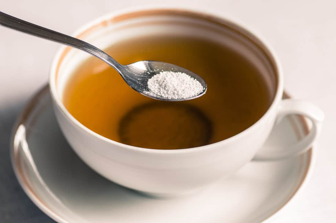 Cup of tea with sweetener sorbitol in a spoon