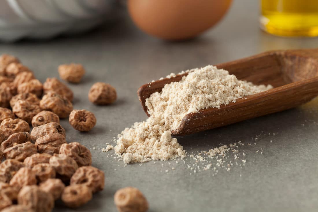 Wooden scoop with tigernut flour and shelled tigernuts