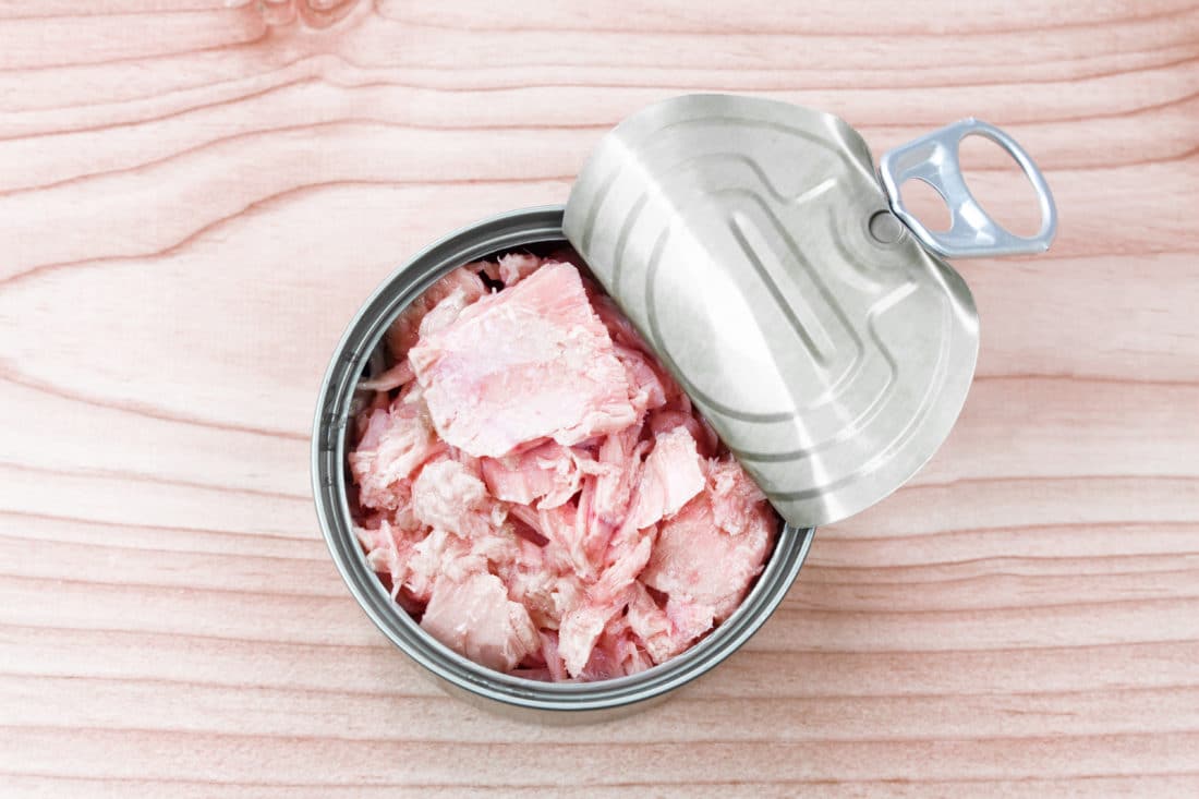 canned tuna on wood table / Canned albacore pink meat tuna packed in water