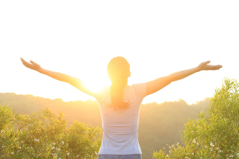 woman standing in the sun with arms wide open