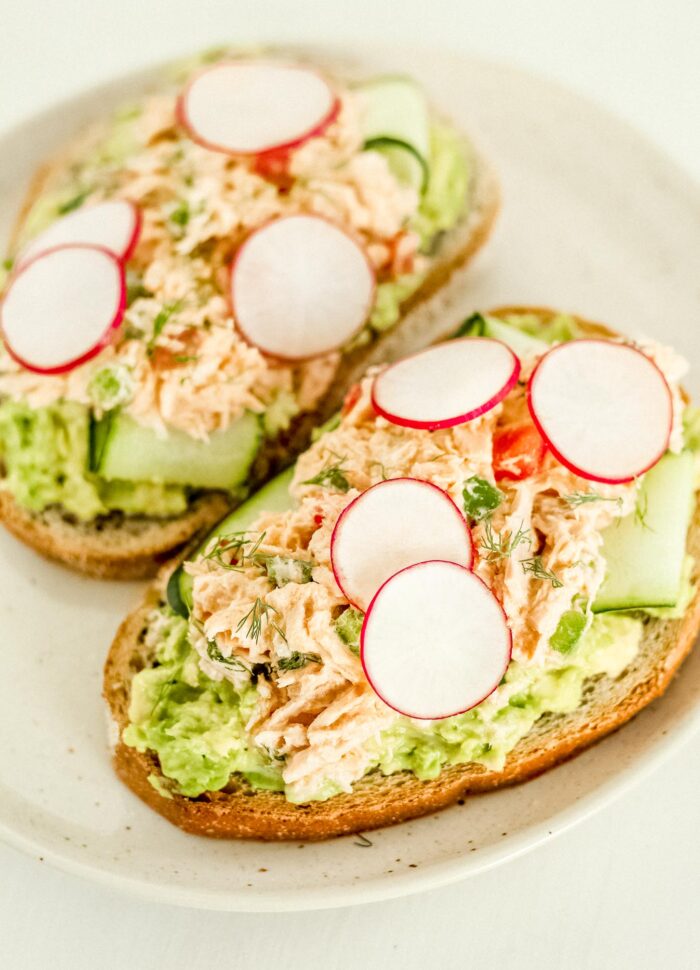 Spicy tuna salad on avocado toast with cucumber and radish.