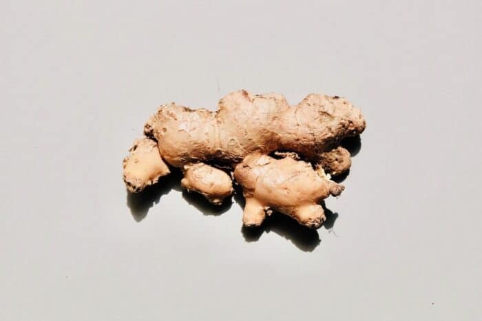 Ginger shot benefits - a large piece of fresh ginger on a gray background. 